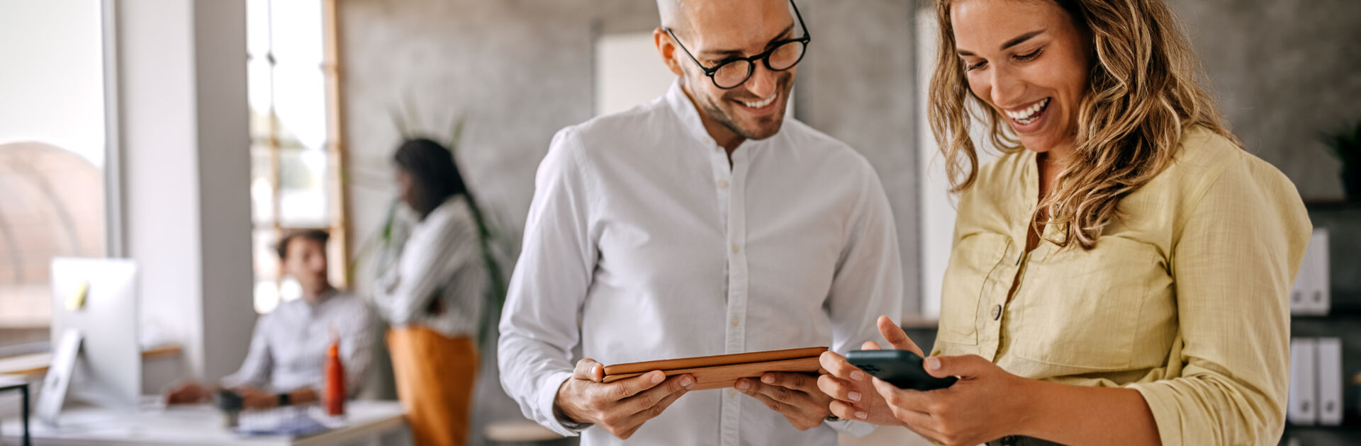 Businessman and businesswoman smiling looking at phone